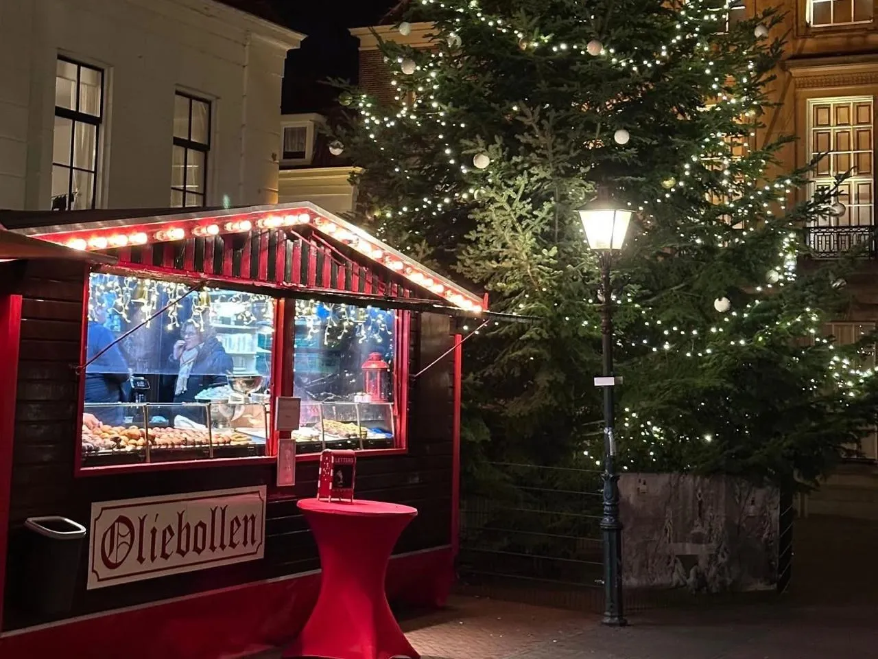 De oliebollenkraam van Burggraaf bij avond op de Markt in Brielle, naast de verlichte kerstboom